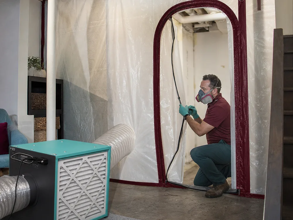 Basement mold work zone with containment sheeting, zipper door and filtered air machine